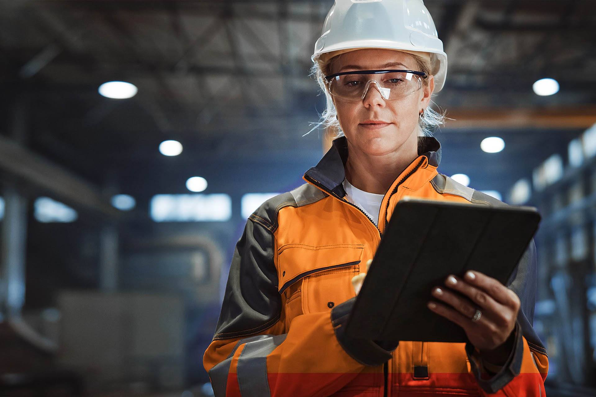 Field worker in construction overalls with hardhat using tablet computer